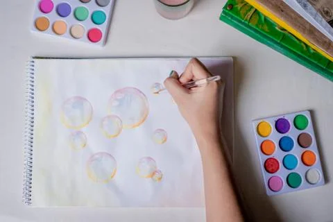 Hand coloring bubble drawing with colored watercolors in a sketchbook Stock Photos