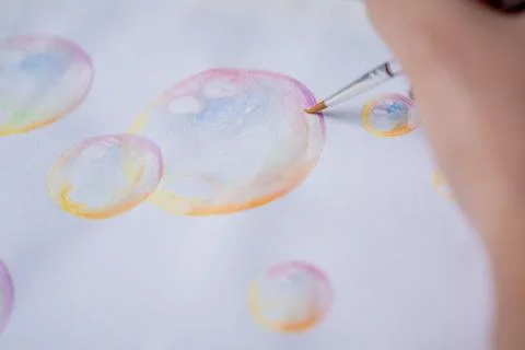 Hand coloring bubble drawing with colored watercolors in a sketchbook Stock Photos