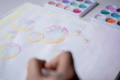 Hand coloring bubble drawing with colored watercolors in a sketchbook Stock Photos