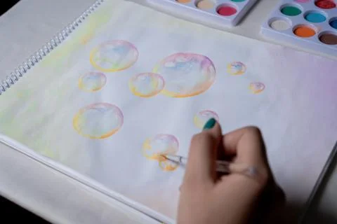 Hand coloring bubble drawing with colored watercolors in a sketchbook Stock Photos