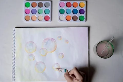 Hand coloring bubble drawing with colored watercolors in a sketchbook Stock Photos