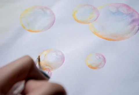 Hand coloring bubble drawing with colored watercolors in a sketchbook Stock Photos