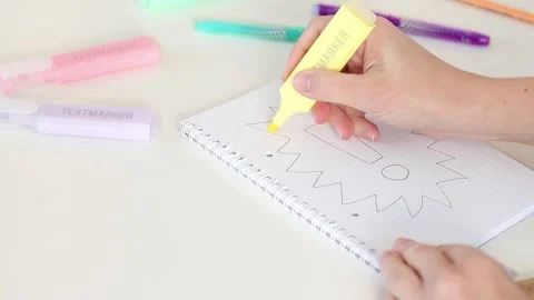 Hand coloring exclamation mark with yellow marker in notebook on white table Stock Footage 331802193