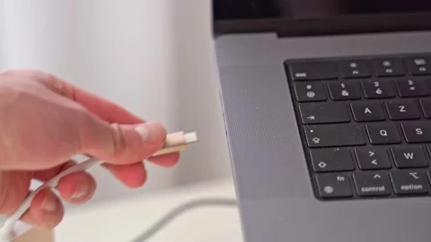 A hand comes into the close-up scene and plugs in a USB-C adaptor for Stock Footage 213798472
