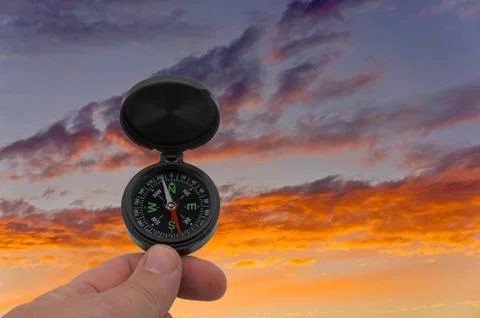 Hand with compass on background evening sky Stock Photos