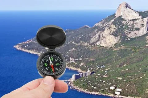 Hand with compass on background mountains Stock Photos