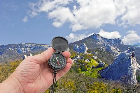 Hand with compass on background mountains Stock Photos