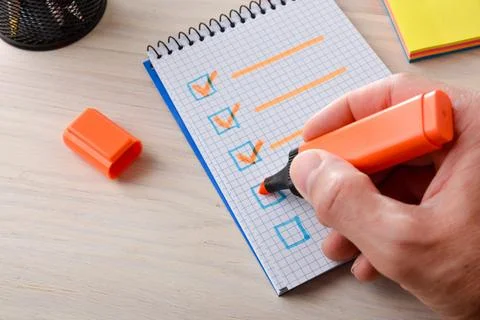 Hand Completing Checklist with Orange Marker Stock Photos
