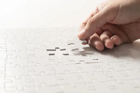 Hand completing white puzzle Stock-Fotos