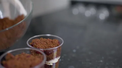 Hand of confectionery, which is distributing chocolate dough to the glass Vídeo Stock 85617742