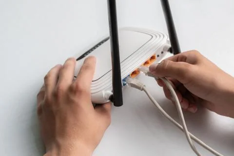 Hand conncecting the ethernet wire cable with wi-fi remote point Foto stock