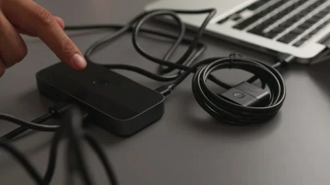 Hand connecting compact black external hard drive to laptop with USB cable on Stock Footage 347533491