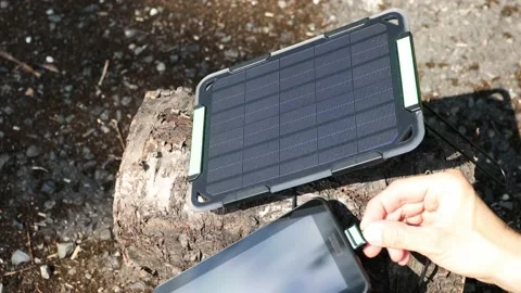 Hand connecting tablet to portable solar panel to charge from sunlight. 스톡 동영상 157483959