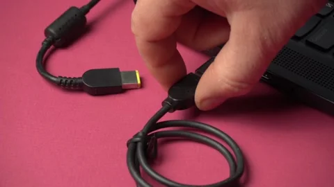 Hand connects USB cable to laptop port, showcasing the process of plugging in Stock Footage 329619749