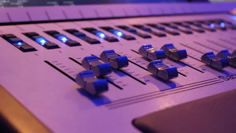The hand controls the faders on the light console Stock Footage 231556442