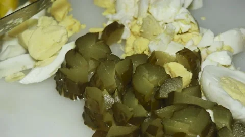 The hand of the cook cuts the boiled egg next to the pickled cucumber Vídeos de archivo 231199223