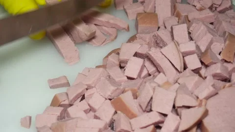 The hand of the cook with a knife cuts the boiled sausage into pieces, for s Vídeos de archivo 229560269