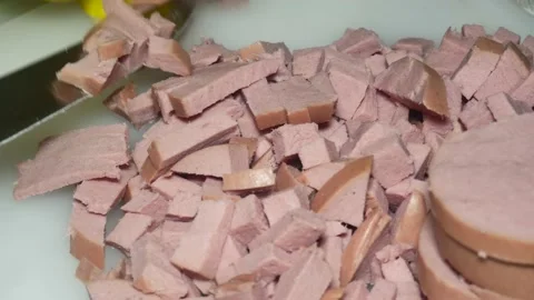 The hand of the cook with a knife cuts the boiled sausage into pieces Vídeos de archivo 229560360