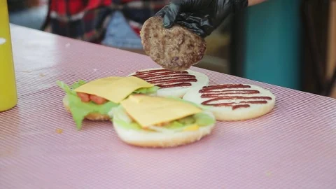 Hand of the cook puts fried cutlets on burger's buns Stock Footage 85360345