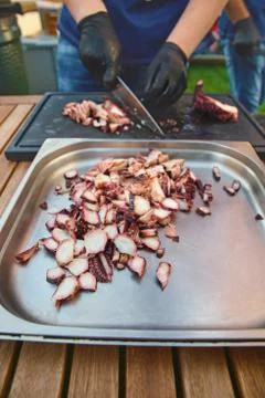 Hand cook using knife cutting squid slices on stove Stock Photos