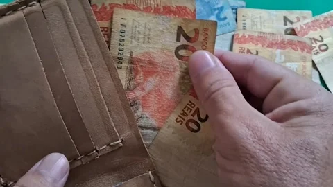 Hand counting Brazilian banknotes inside brown leather wallet motion video Stock Footage 339497582