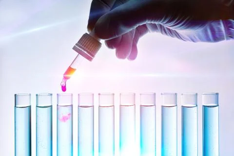 Hand with counting drops dropping red solution into test tubes Stock Photos