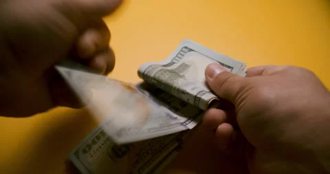 Hand Counting Stack of $100 Bills on Yellow Background 스톡 동영상 307862997