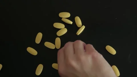 Hand Counting Yellow Pills Top View Video stock 340340997