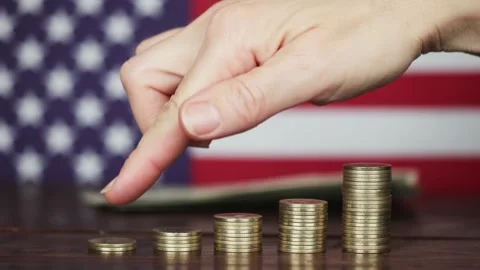 A hand counts dollar banknotes and points to gold coins Stock Footage 300168540