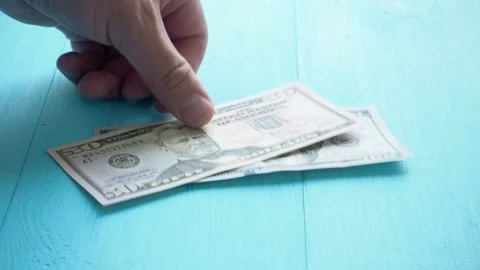 Hand counts dollars and puts them on the blue table Stock Footage 138165835