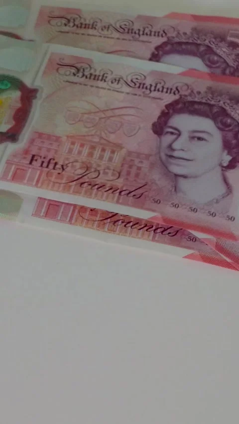 Hand counts out £1,000 in £50 notes onto a white surface, building a Stock Footage 334239892