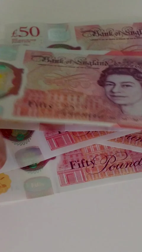 Hand counts out £500 in £50 notes onto a white surface, building a dishevelled Stock Footage 334241400