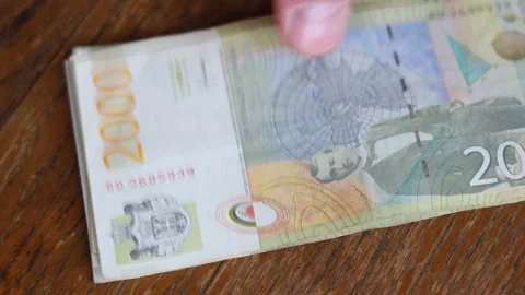 Hand counts paper banknote 2000 dinar on wooden table Stock Footage 348765771