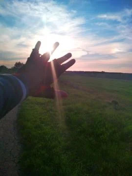 Hand covering the sun in beautiful field. Sunrise Stock Photos