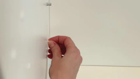 Hand covering unused shelf support hole with plastic cap in cabinet panel close Stock Footage 330933566