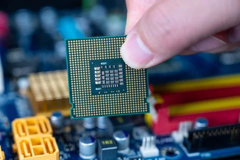 Hand with CPU on a computer motherboard. Stock Photos