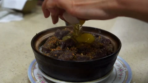 Hand crack egg in black rice clay pot Hong Kong Cantonese style Chinese food Vídeos de archivo 126480707