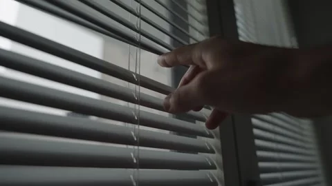 Hand crack opens shutter or window blinds to peek at the street outside Vídeo Stock 257792519