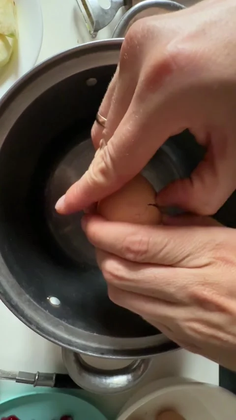 Hand cracking raw egg into metal cooking pot from above Stock Footage 337482505
