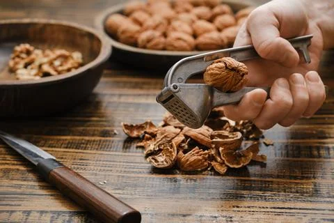 Hand cracking walnuts with nutcracker in a kitchen setting during the afterno Foto stock