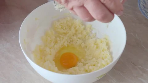 Hand cracks an egg into a white bowl with butter mixture while preparing doug Stock Footage 337883048