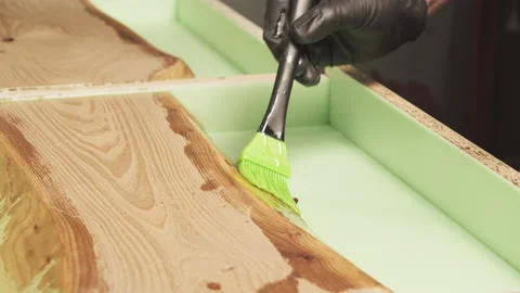 Hand of a craftsman applying varnish or primer with a brush on a wooden tabletop Stock Footage 135670802