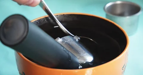 The hand of a craftsman cleans with a spoon the inside surface of a coffee Stock Footage 337831099