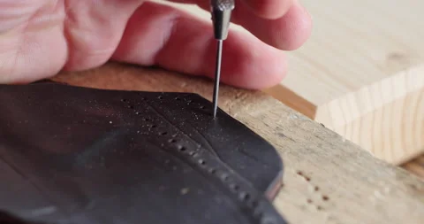 Hand of craftsman punching hole in piece of natural leather. leathergoods Stock Footage 140973653