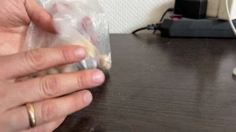 A hand crinkles a plastic bag filled with mixed nuts Stock Footage 335074439
