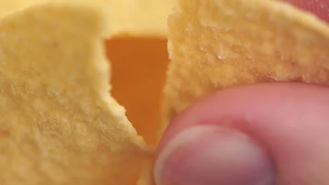 Hand crushing potato chips, macro view, rotation. Crispy potato rotating cl.. Stock Footage 257585714