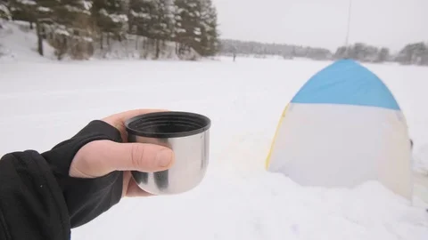 Hand with a cup against the backdrop of a winter tent Stock Footage 124046621