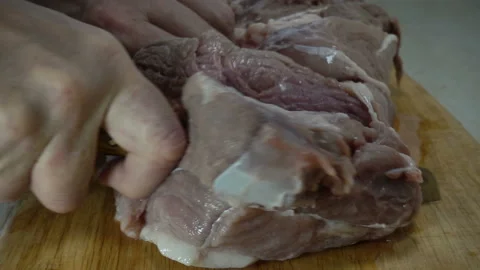 Hand cuts a piece of raw meat in slow motion Stock Footage 135969696