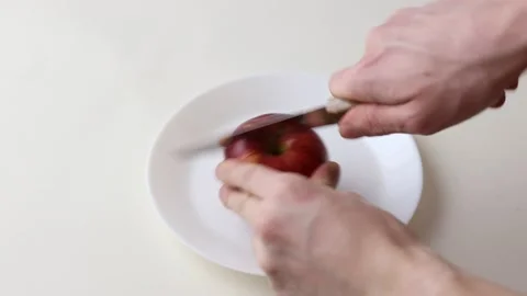 A hand cuts a red apple with a knife Stock Footage 145536907