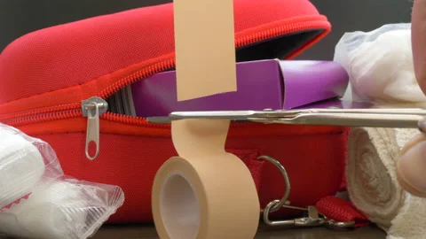Hand cutting adhesive tape with scissors from a first aid kit. Stock Footage 180876640